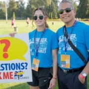 Two volunteers in sunglasses and t-shirts from the 2024 BC Summer Games smiling for the camera.