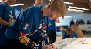 Team BC athlete writes a thank you message to host society on a banner